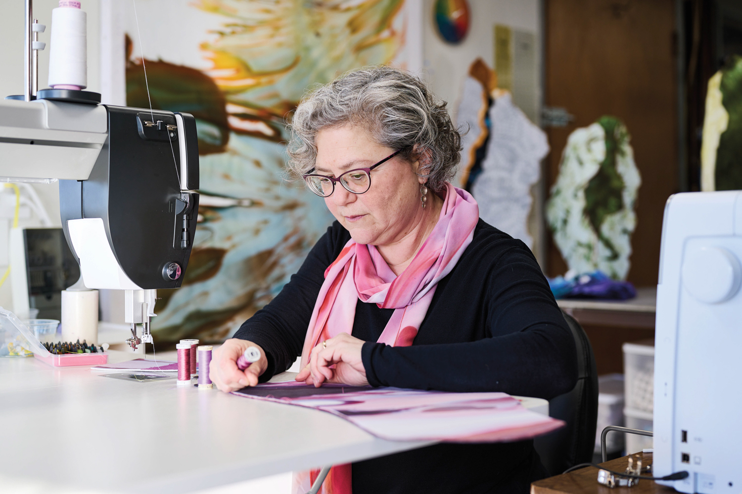 Artist Cameron Anne Mason sits at a sewing machine