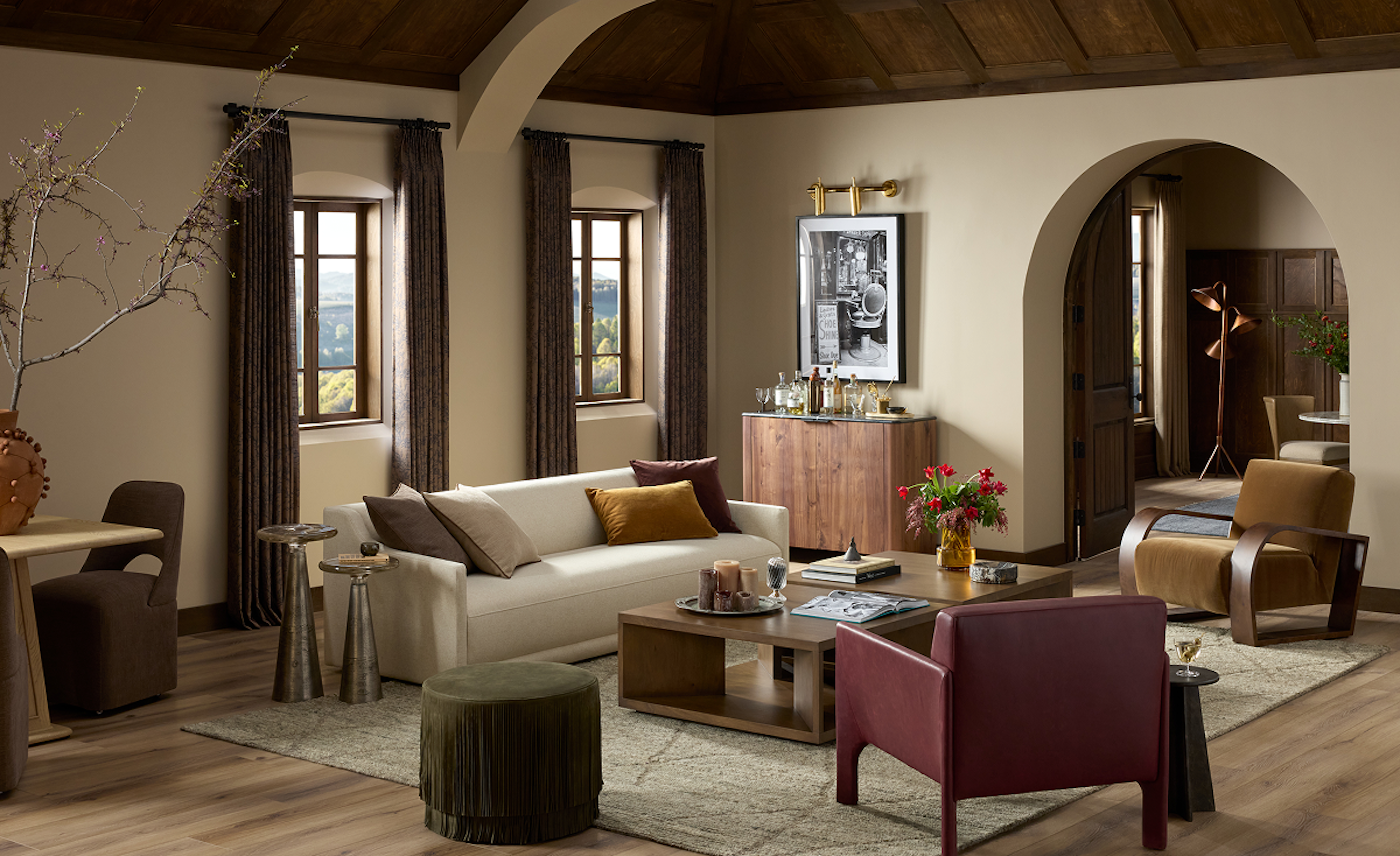 Elegant living room with a beige sofa, colorful cushions, and a mix of modern and vintage furniture. Warm lighting and earth tones create a cozy ambiance.