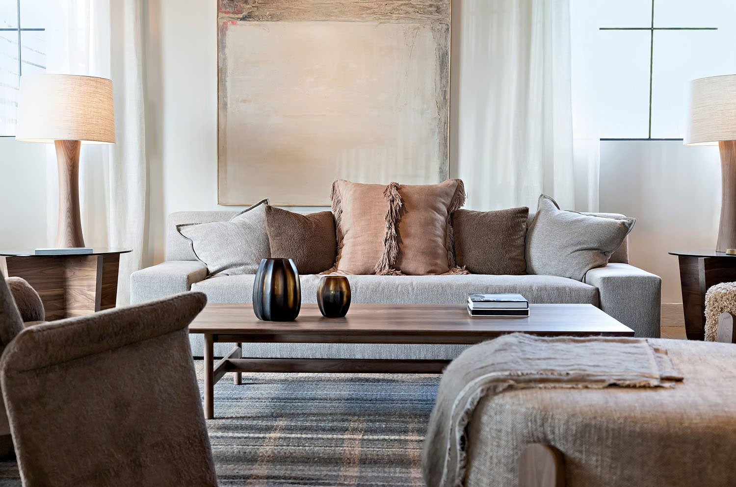 A couch decorated with pillows sits between two floor lamps and is flanked by a coffee table.