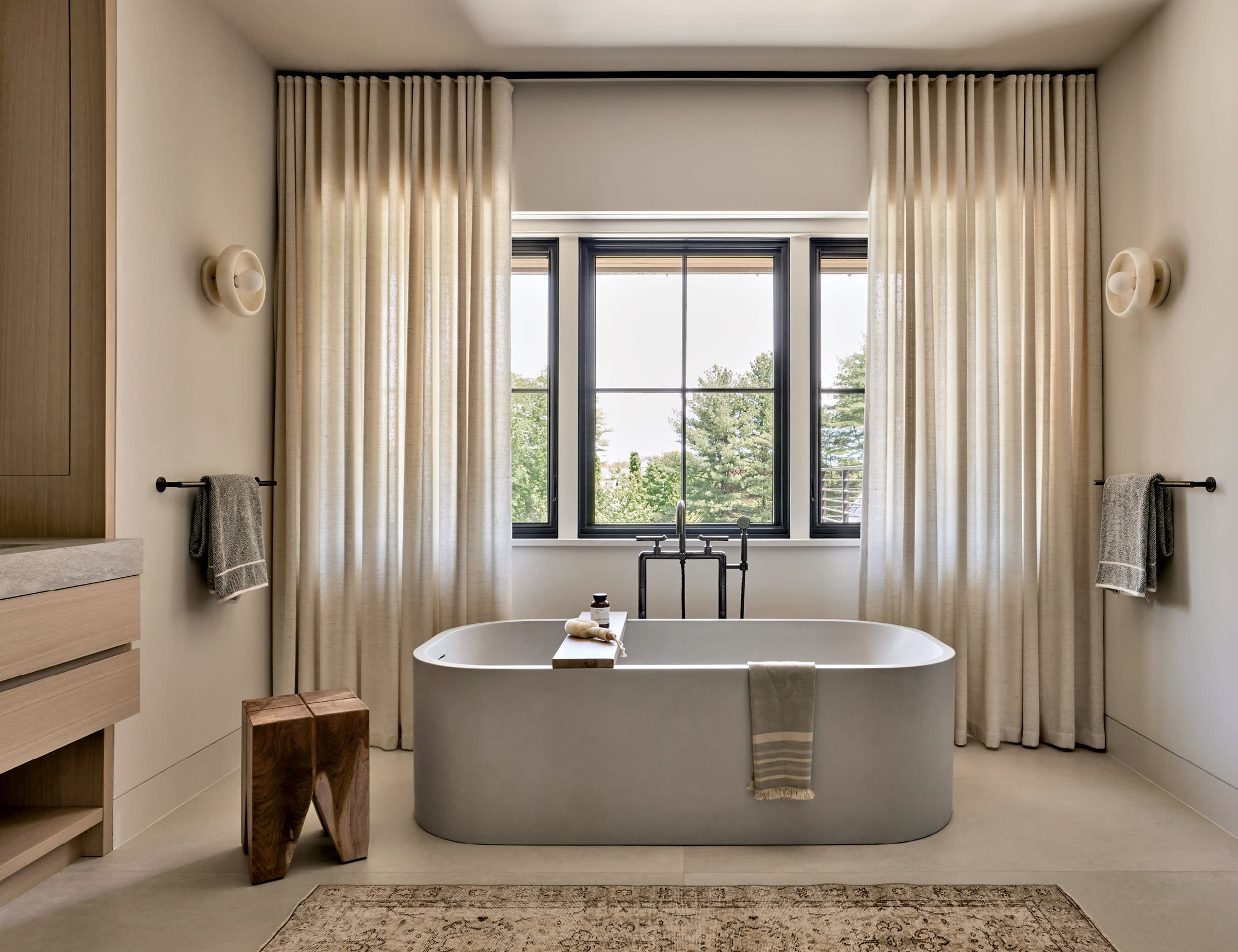 contemporary bathroom with a tan rug and a stone tub