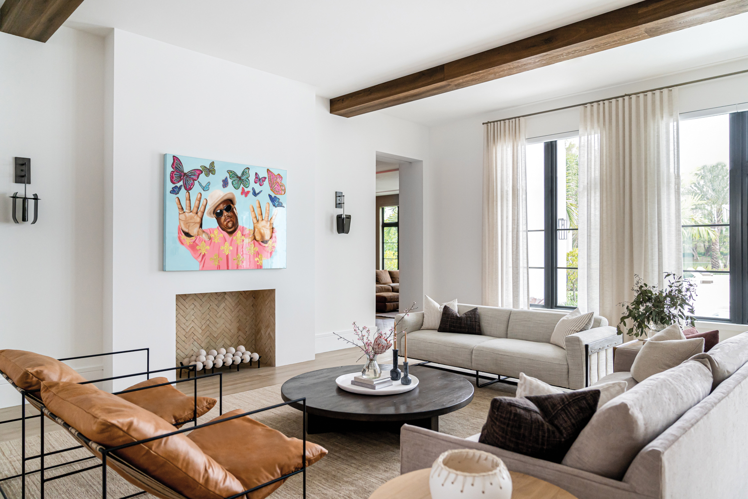 Erin Cantu designs living room with artwork over fireplace, plush chairs and black coffee table