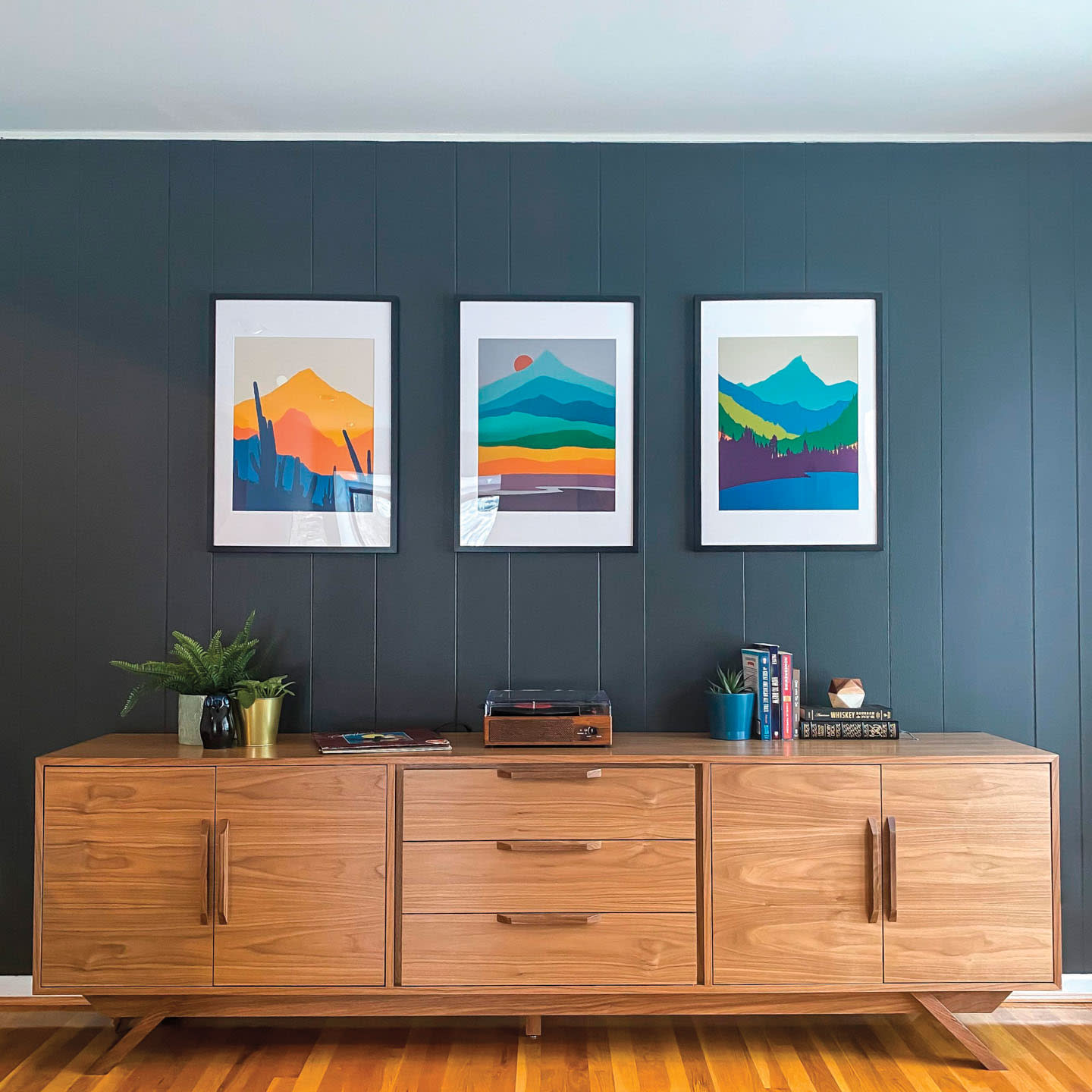 midcentury console in front of a blue wall with three desert-inspired artworks