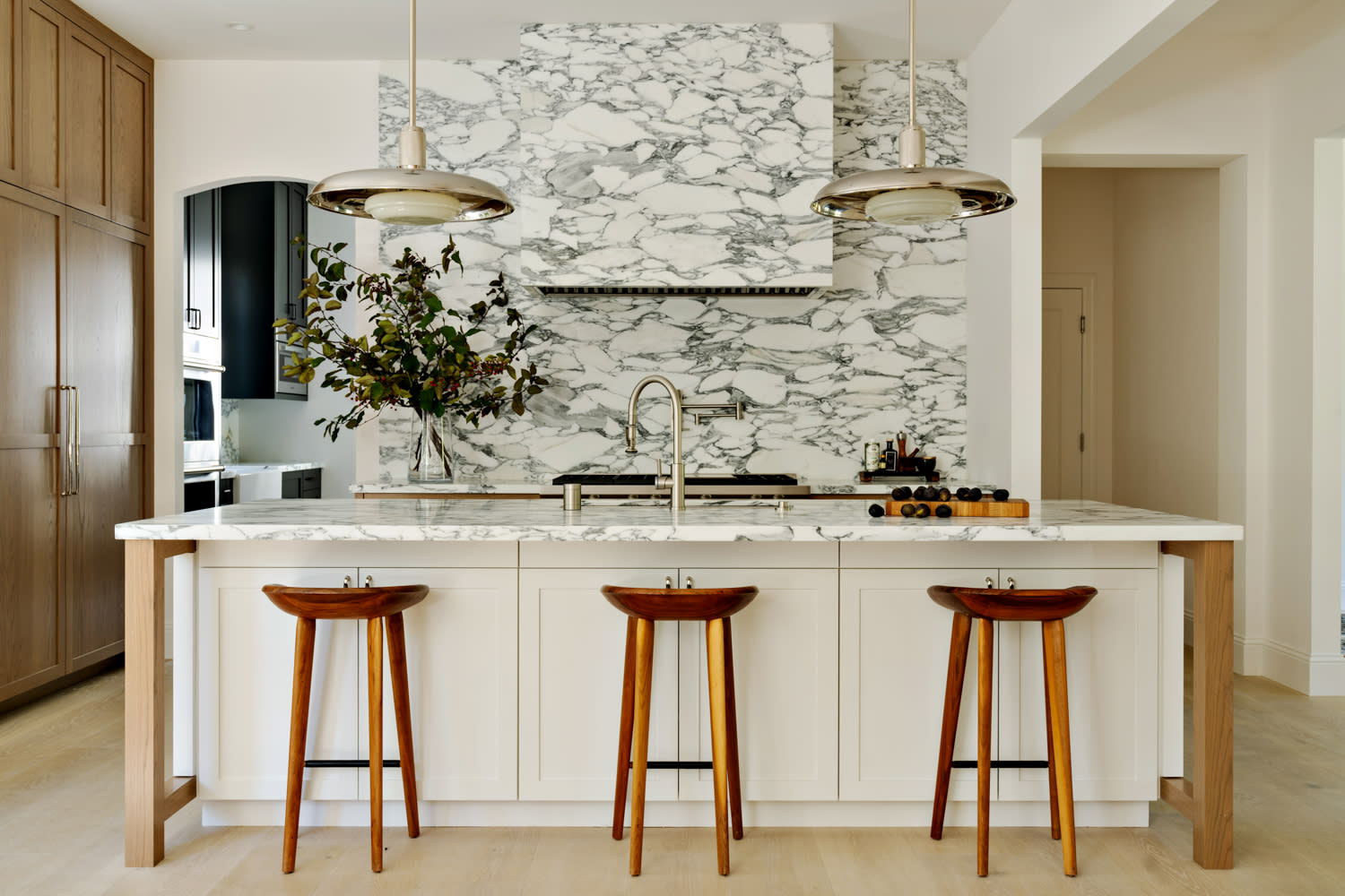 modern kitchen with grey and white marble countertops and natural wood bar stools