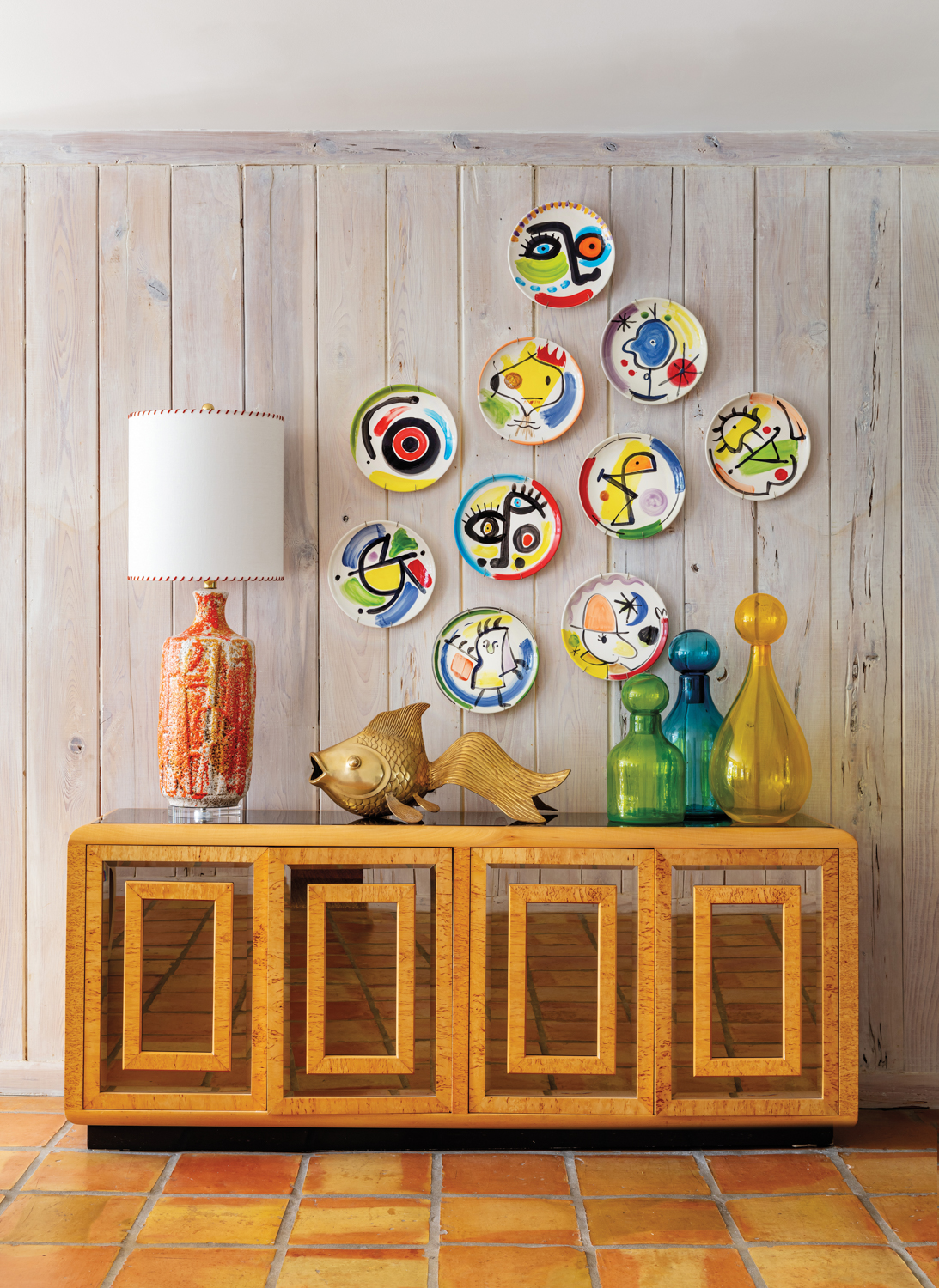 entry area with colorful handpainted plates above a wood console against pecky cypress walls