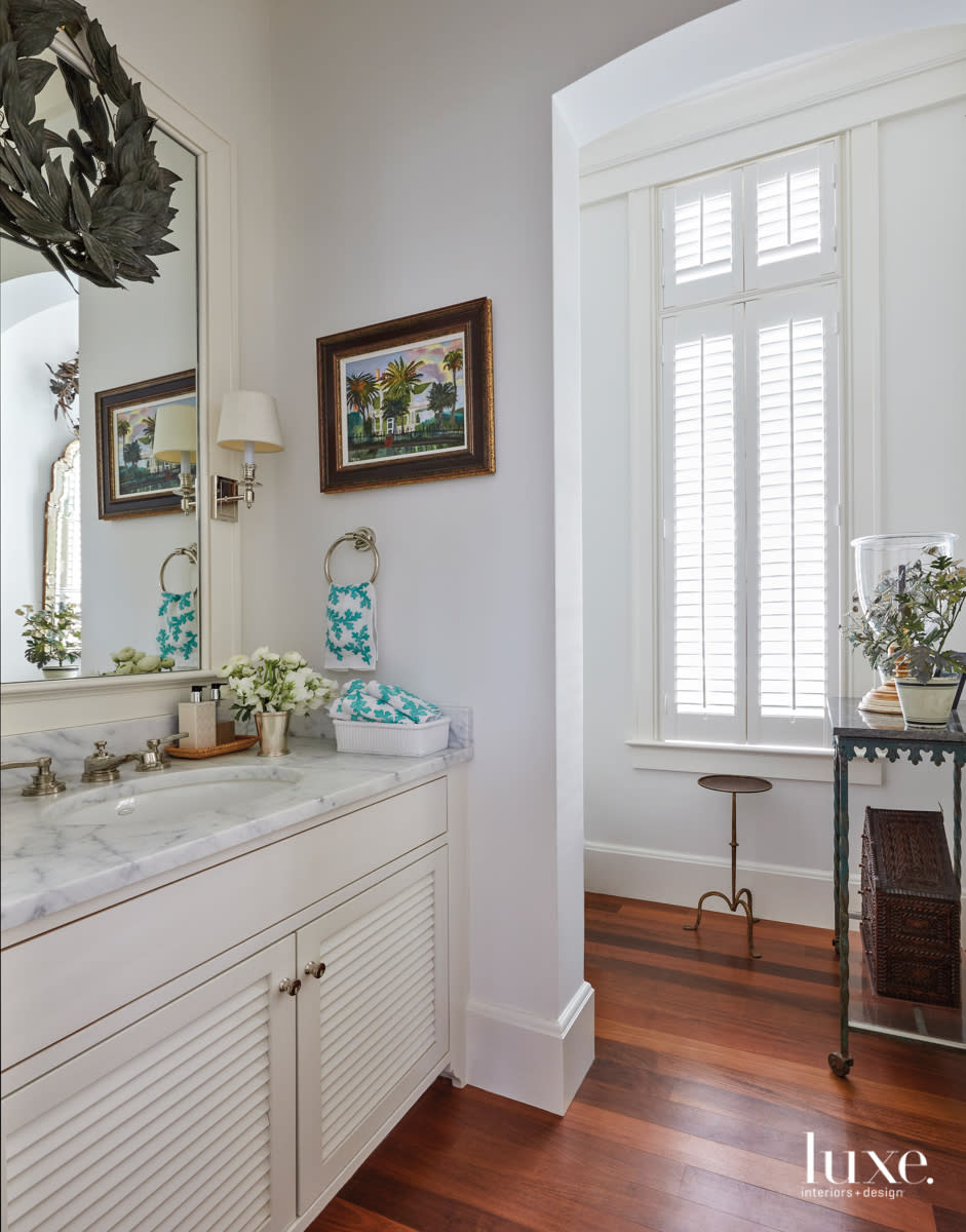 powder room with marble-topped vanity and green metal wreath