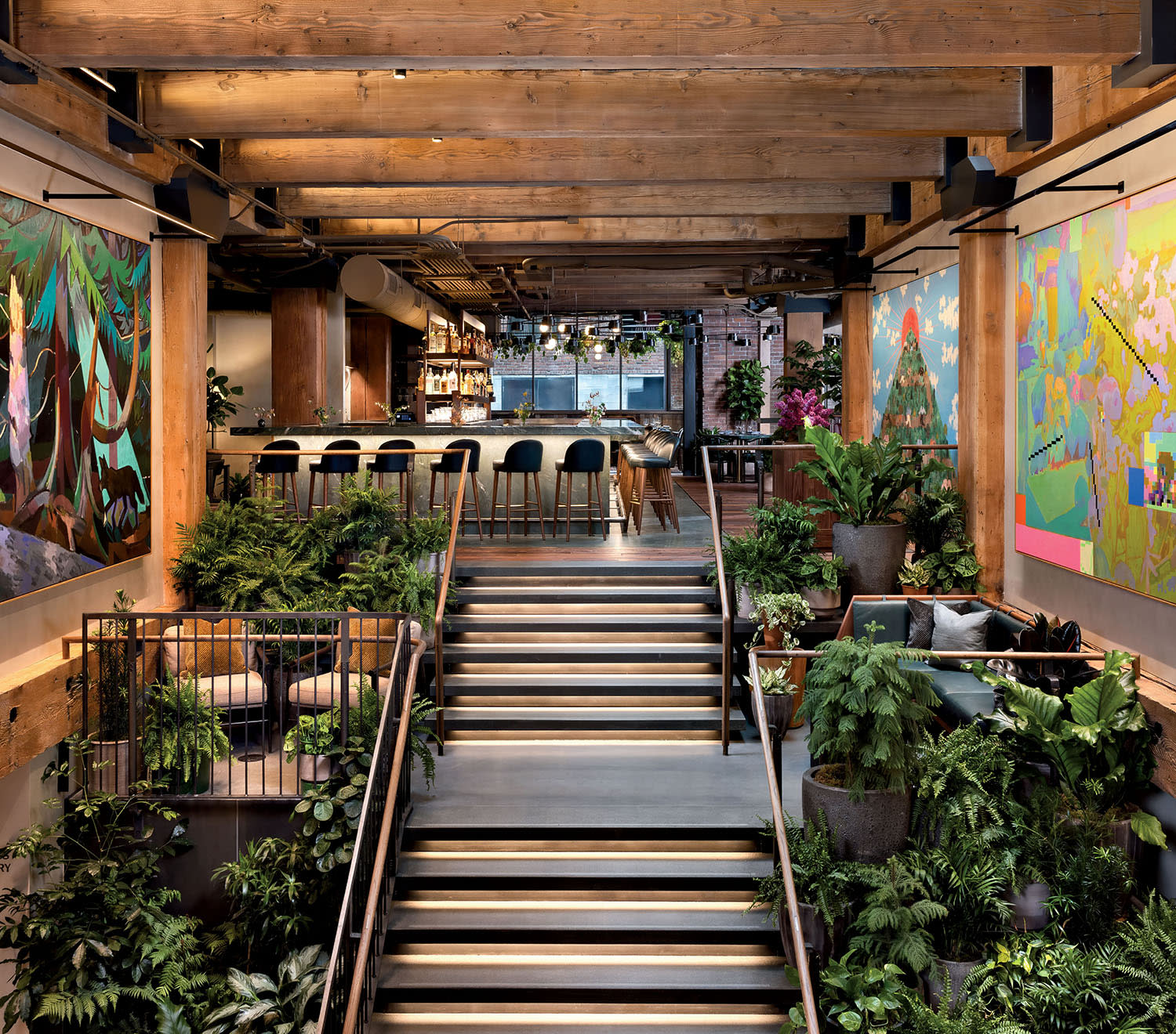 A staircase with greenery on either side leads up to a bar with murals on the walls.