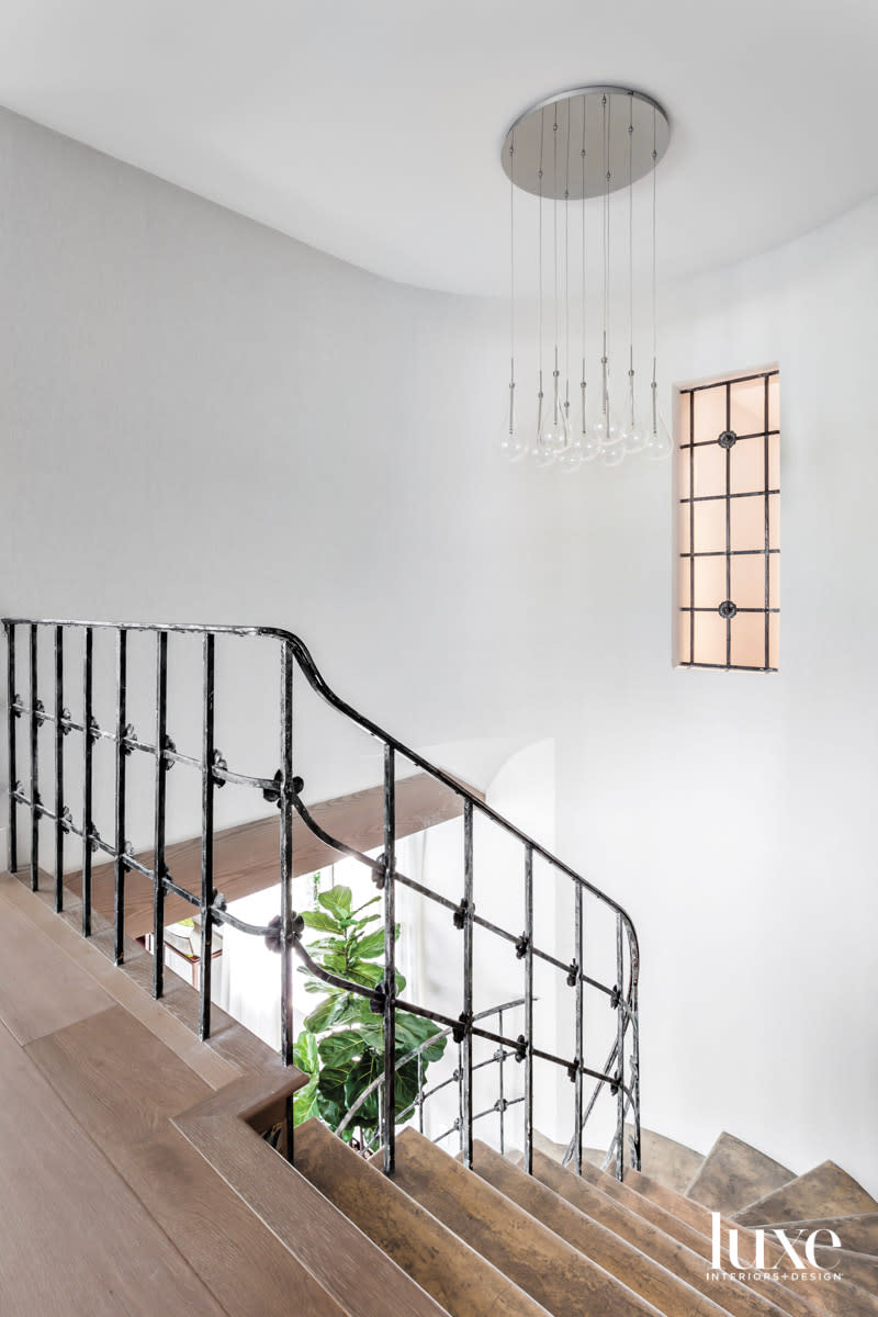 wood staircase with metal-iron railing and teardrop chandelier
