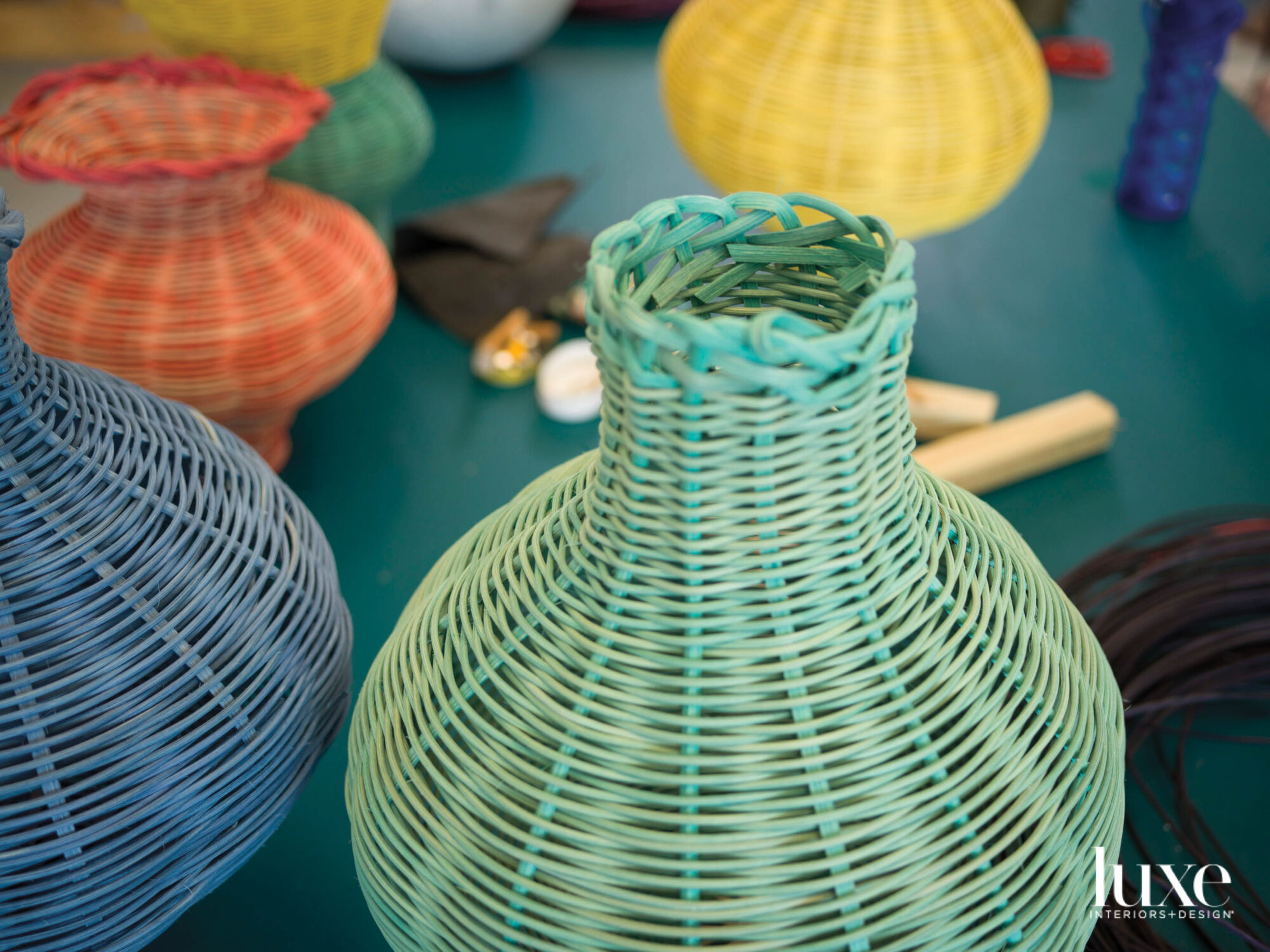 Blue and green woven baskets with orange and yellow ones in the background.