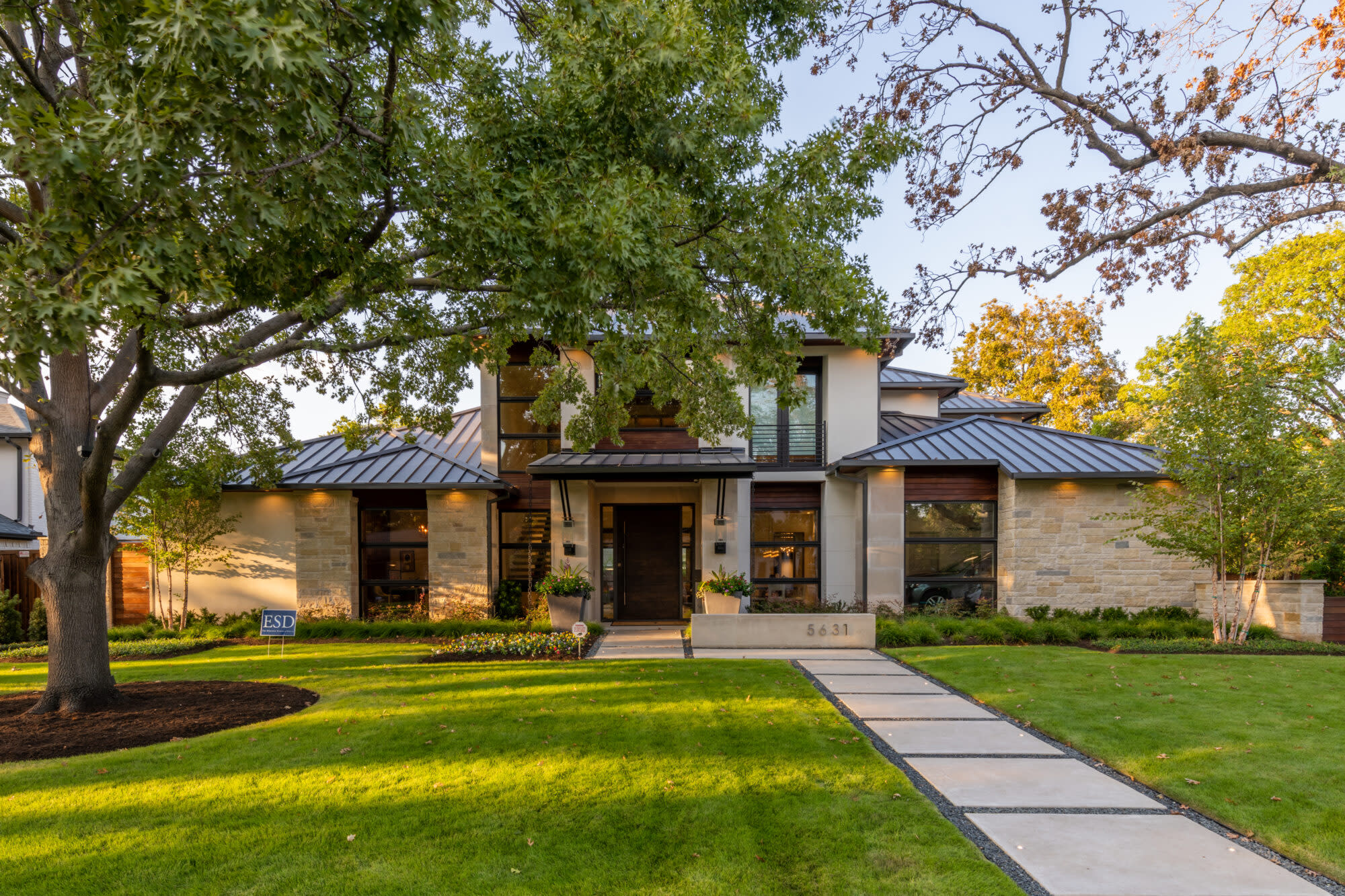 Contemporary home with manicured lawn and stone walkway