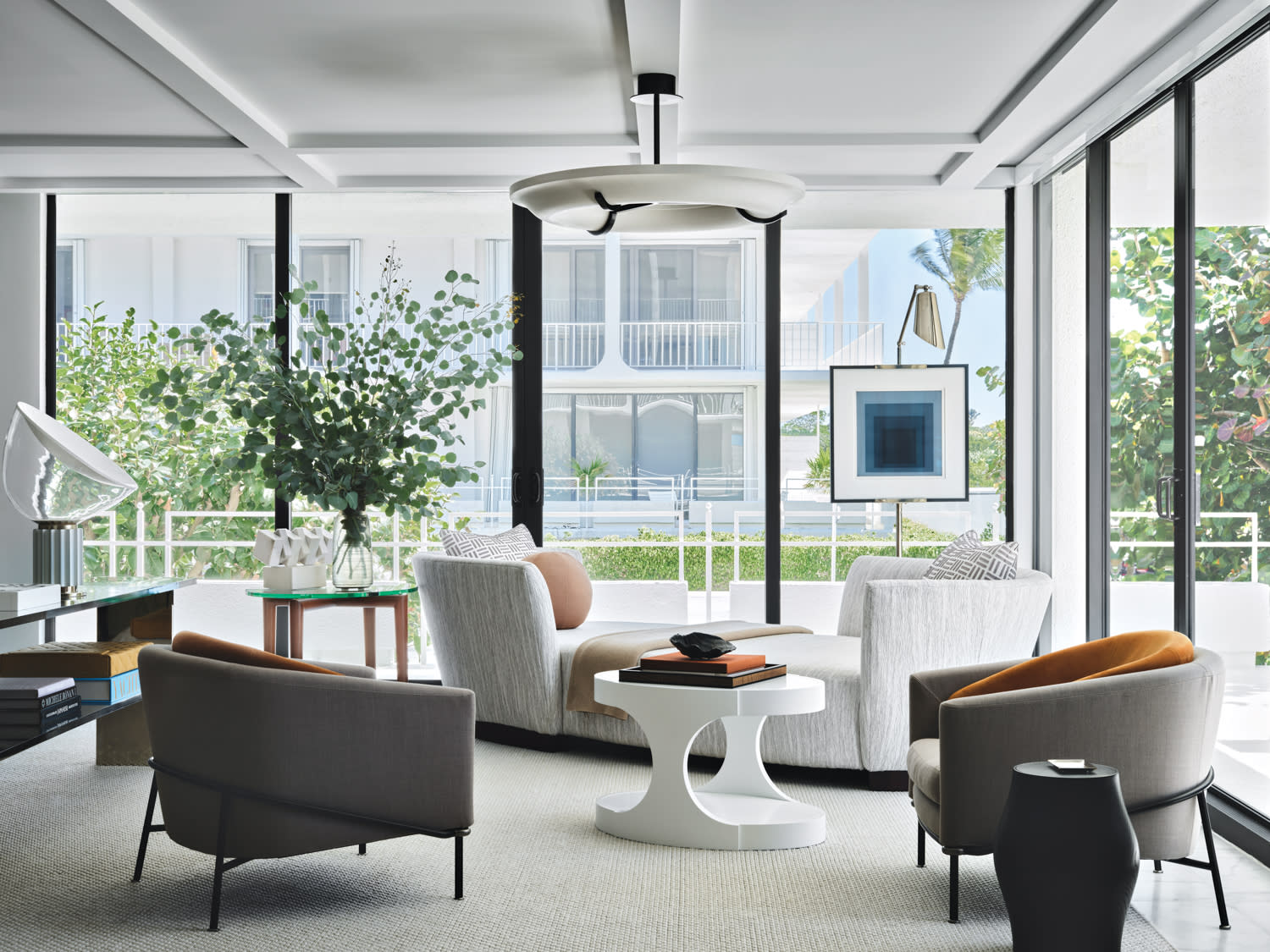 White and grey seating in a living room with floor-to-ceiling wraparound windows