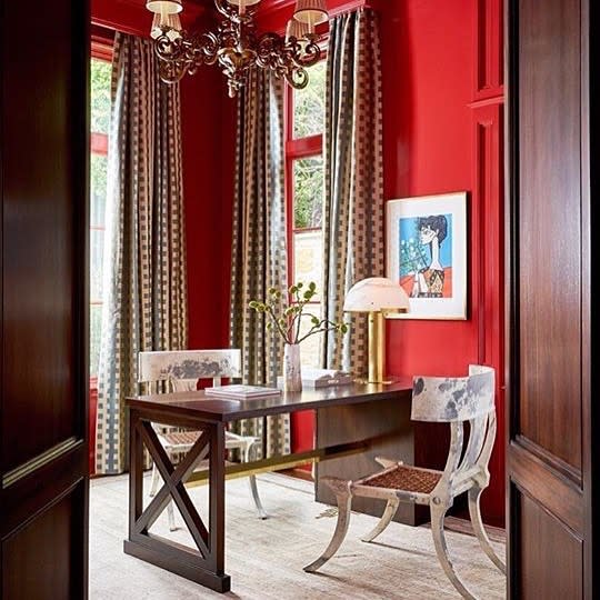 A red room with a desk and chair in an office with red wall paint.