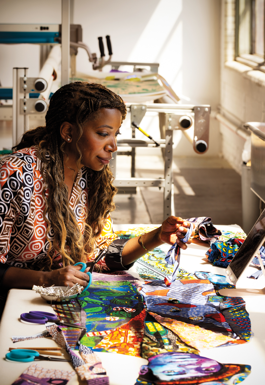 Bisa Butler sits at table looking at textiles