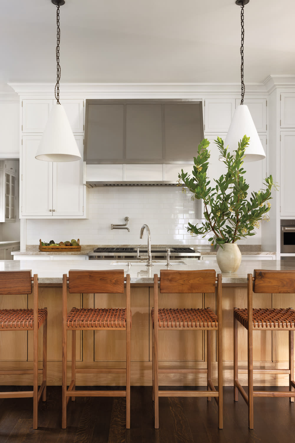 A spacious kitchen featuring a large island and a prominent potted plant, enhancing the room's natural ambiance