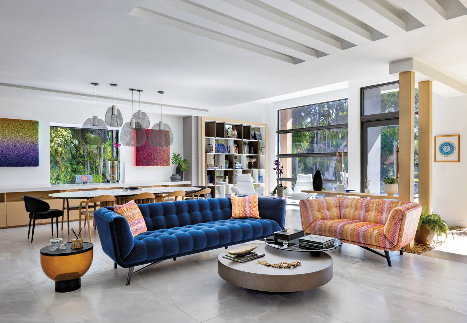 living area with blue loveseat, striped orange loveseat, round grey coffee table and white walls