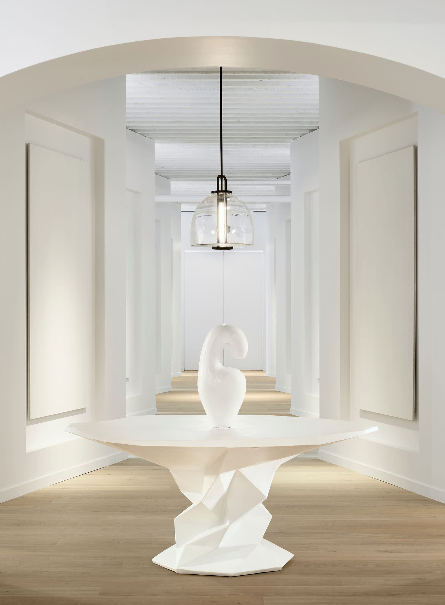 a glass pendant hangs above a sculpture on a table