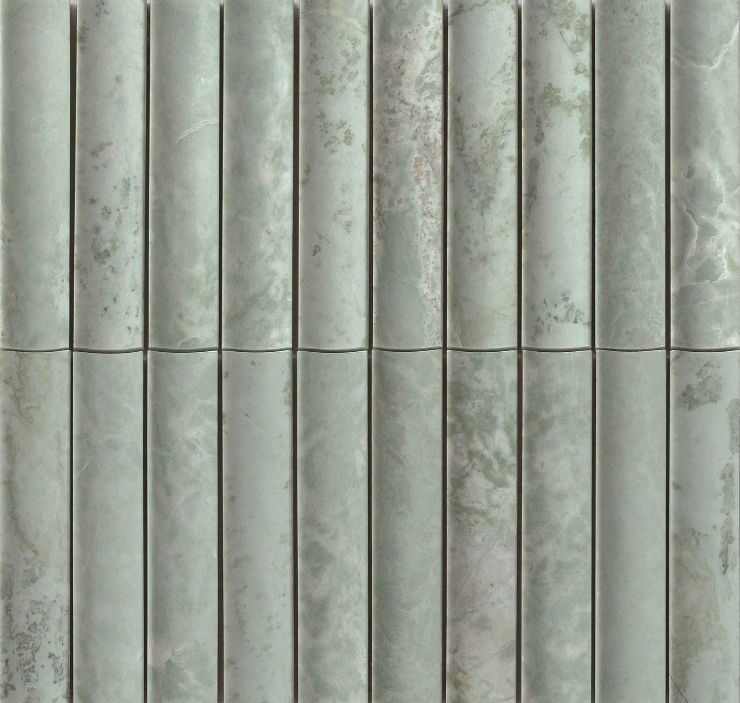 Close-up of a textured green marble wall with vertical, rounded columns. 