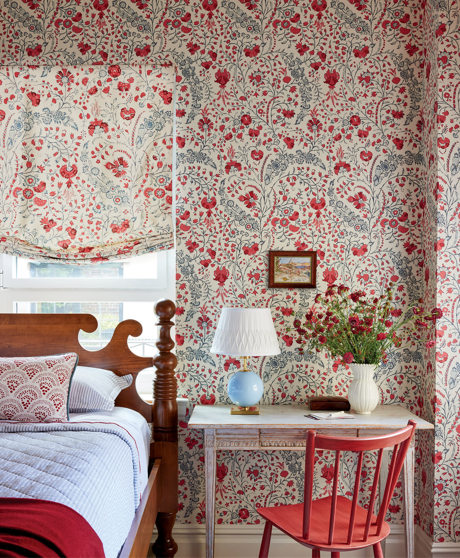 a red and blue paisley print wallpaper surrounds a classic bed