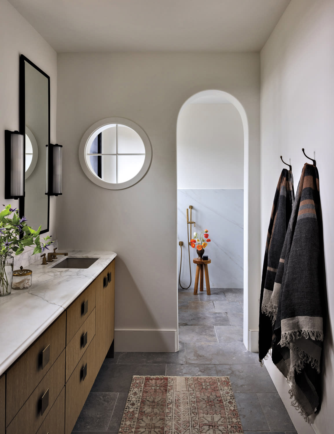 A bathroom with wood cabinets under a white vanity countertop with sink and towels hanging on the wall.