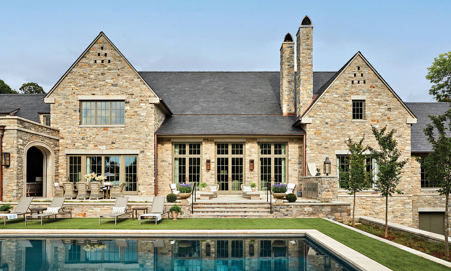 limestone and fieldstone exterior of a traditional home with a pool