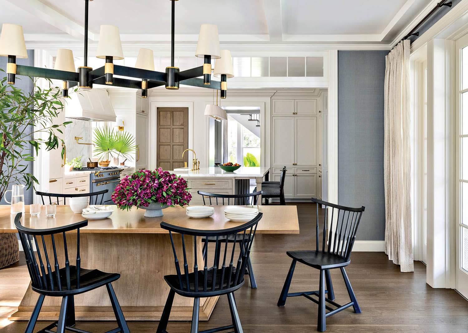 A dining room furnished with a table and dark wood chairs, set near windows with linen curtains.
