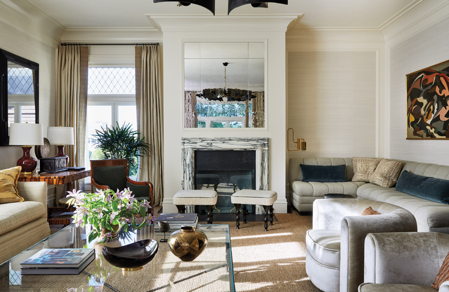 Brightly lit living room with mirror over fireplace and a variety of seating