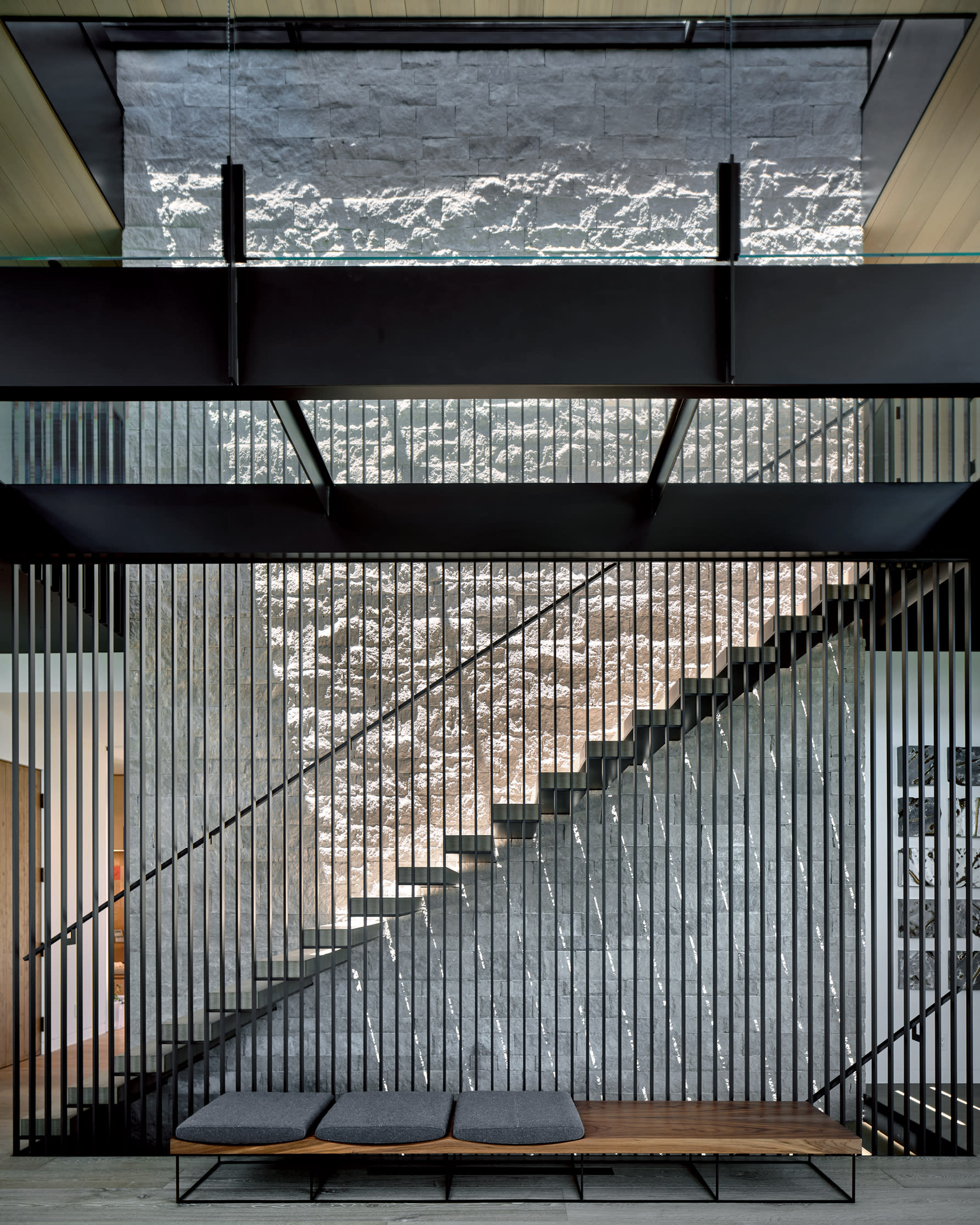 Wood and steel stairway against stone wall 