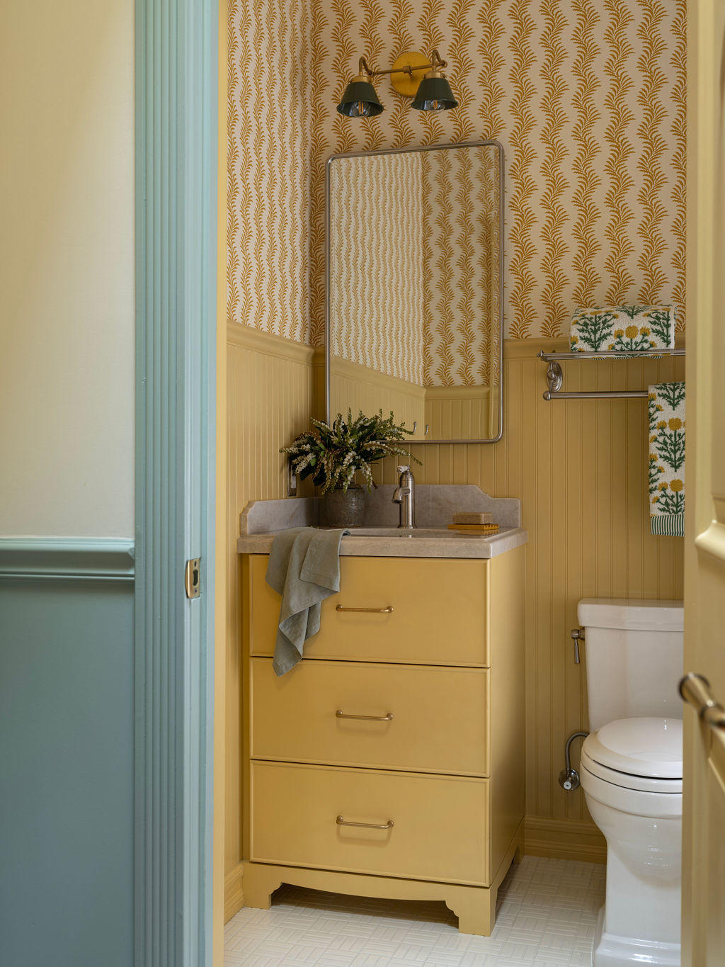 kids bathroom with yellow and white wallpaper and a blue-trimmed doorway