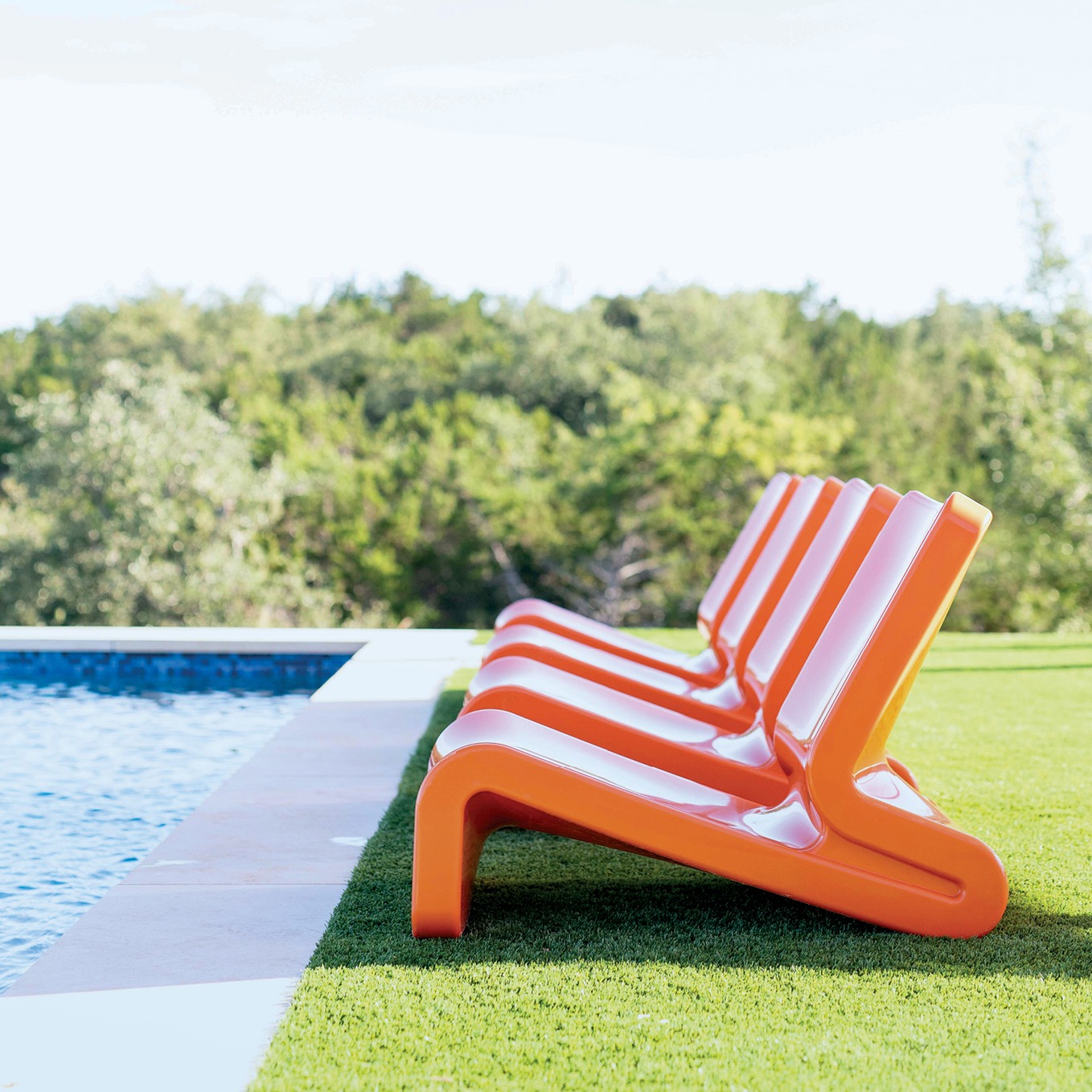 orange outdoor lounge chairs beside a pool