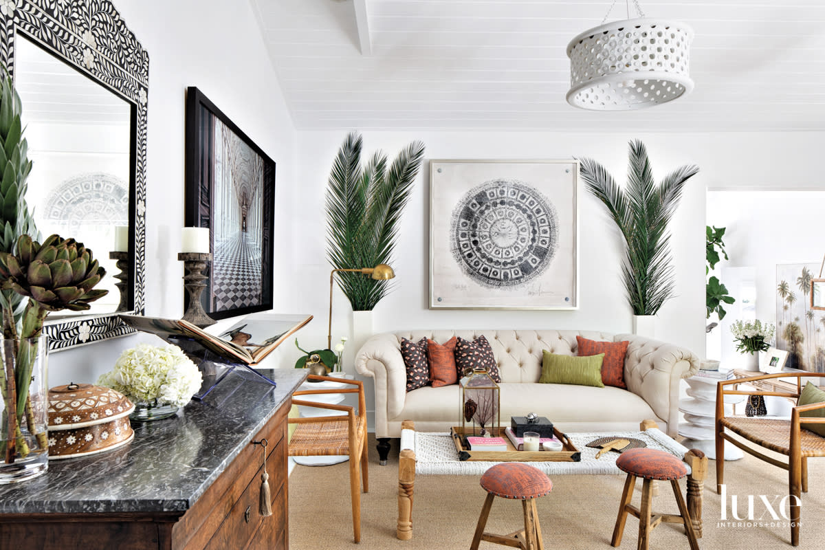 family room with white sofa, red stools and palm fronds