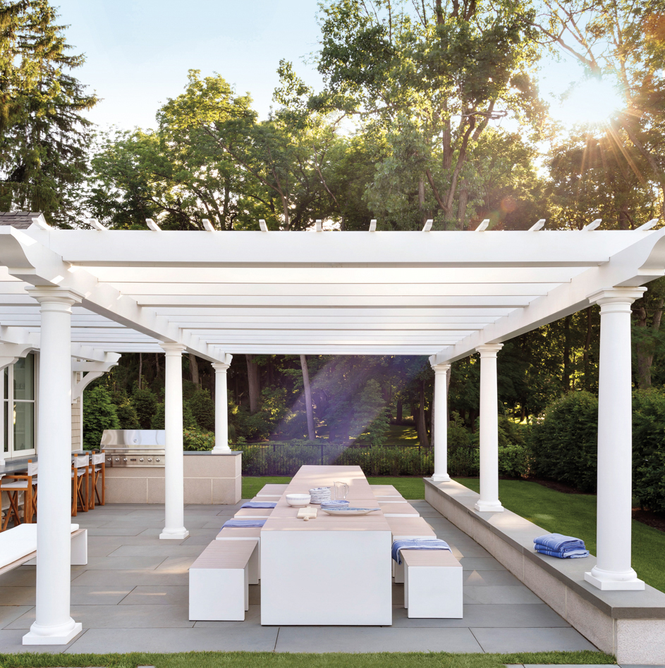 outdoor kitchen dining table under white pergola