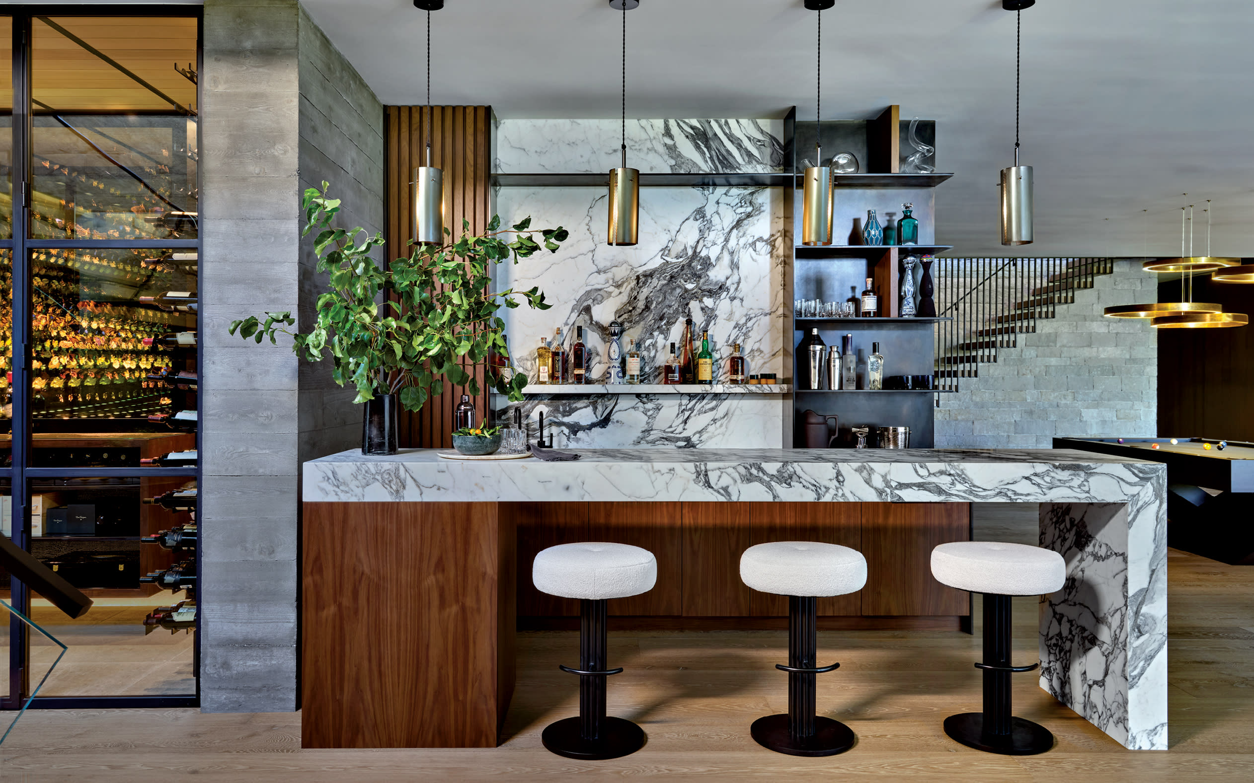 lounge bar with marble backsplash and waterfall island and walnut-and-metal shelves