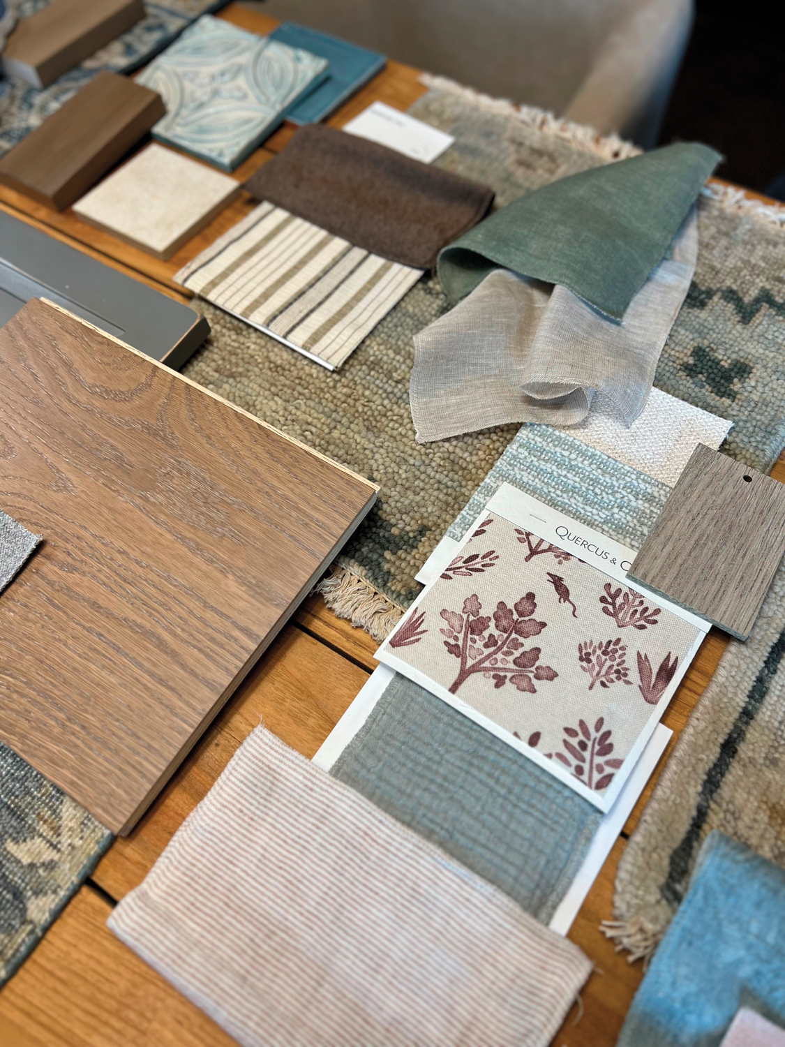 Samples of wood flooring, rugs, tiles and patterned textiles spread across a table