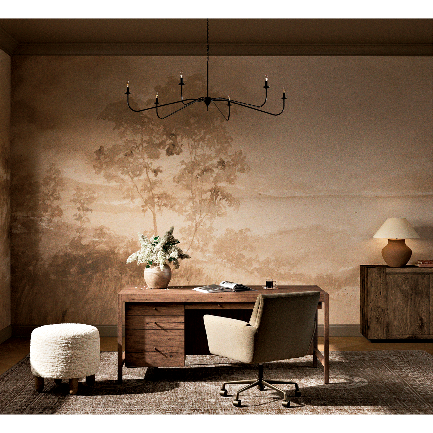 Elegant office with a nature-themed mural, wooden desk, neutral chair, and ottoman on a large rug; chandelier hangs above, creating a serene ambiance.