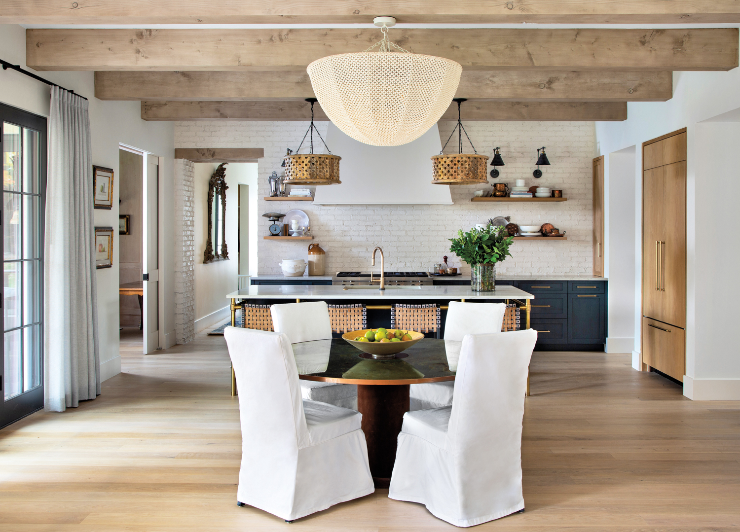 dining area with copper banded vintage table and slip-covered chairs with beaded chandelier overhead