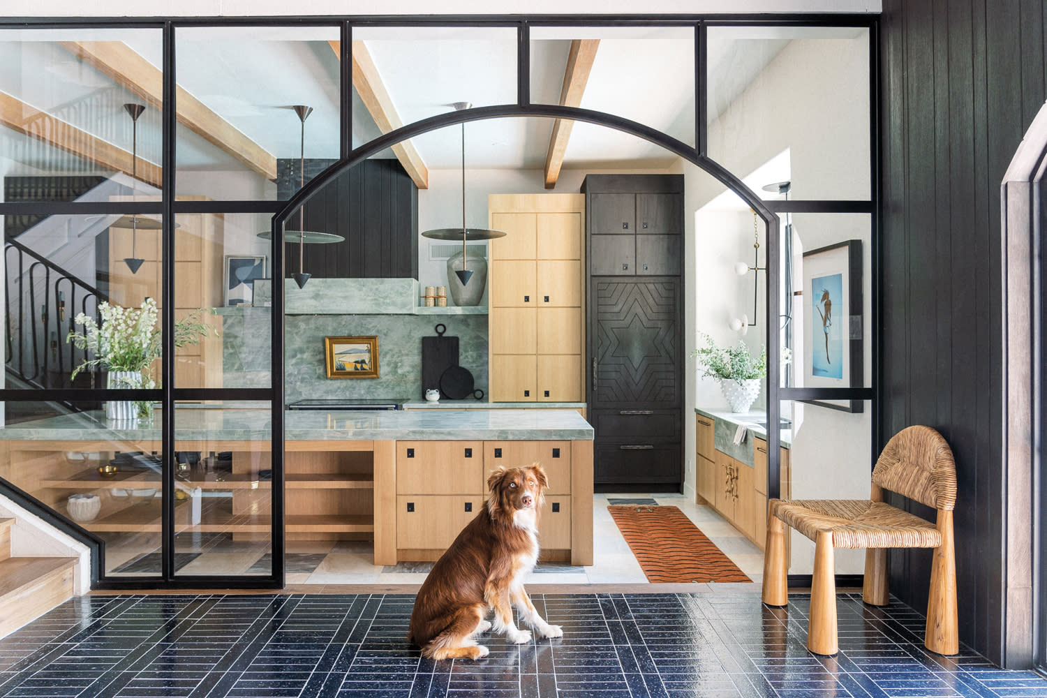 dog sitting in kitchen with arched entryway and green stone backsplash and countertops