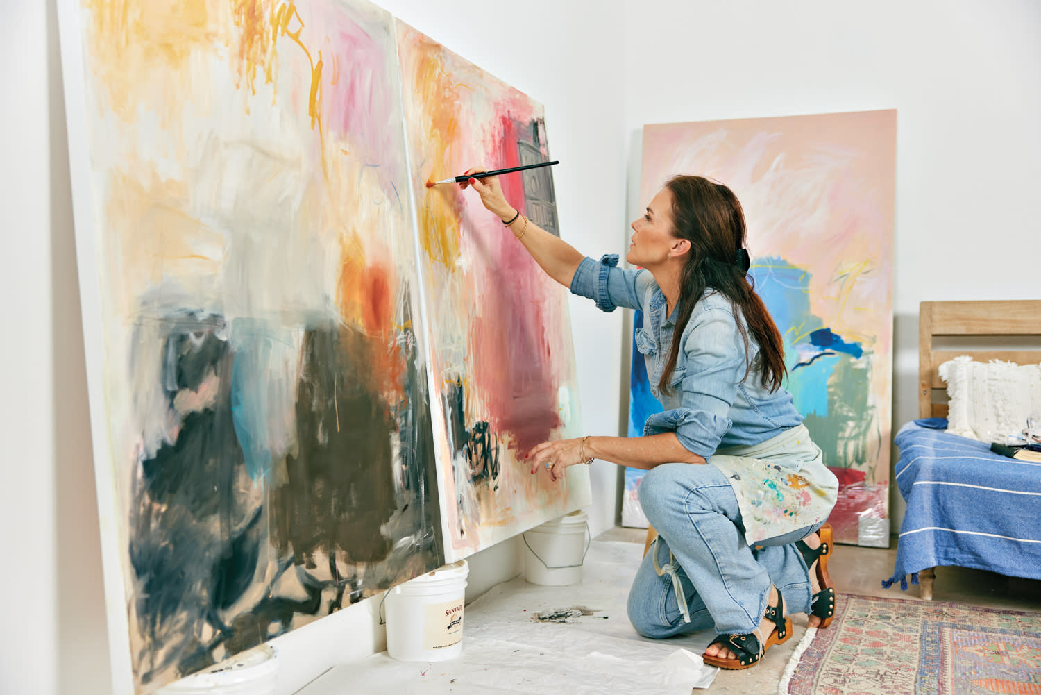 Veronica Pasman kneels while painting a colorful abstract work