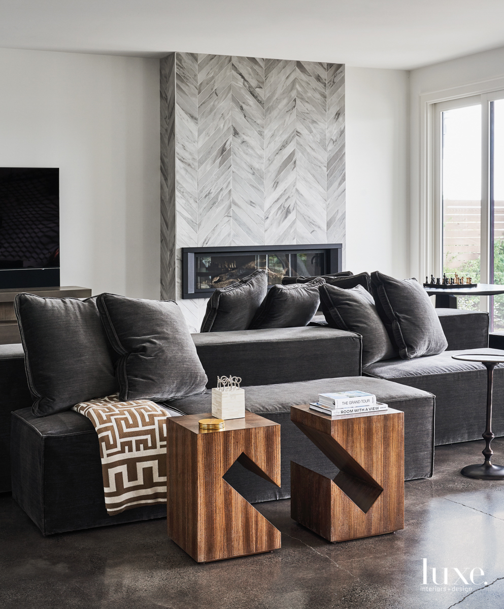 gray chevron tile above fireplace in gray family room and wood side tables