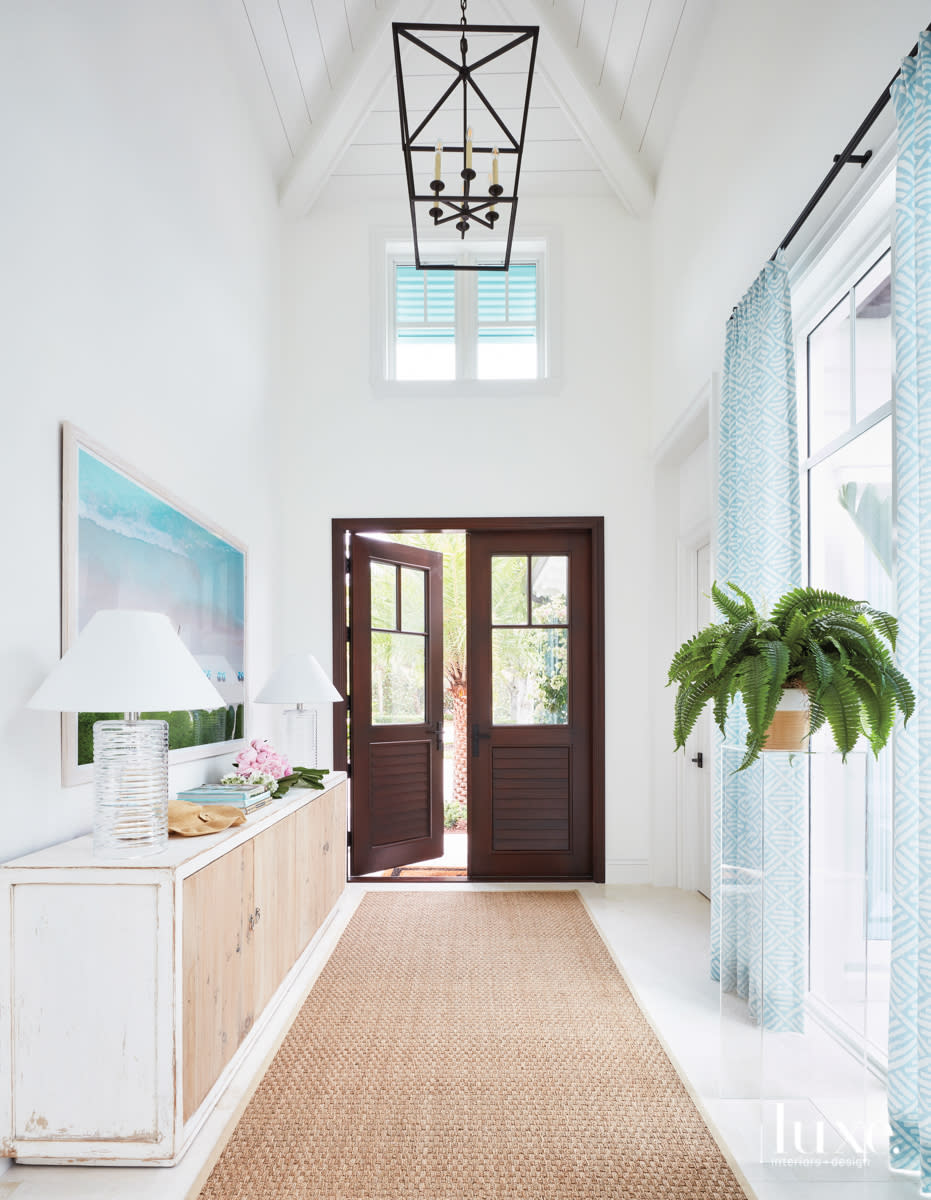Foyer with blue draperies, sisal rug and Gray Malin artwork.