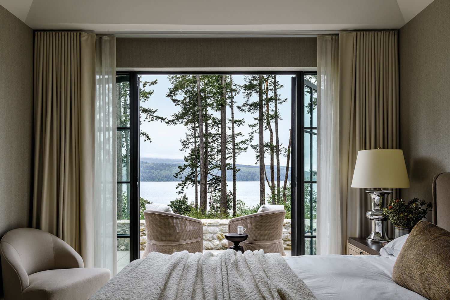 cozy, minimalist bedroom opening to a private terrace on a waterfront home in Washington