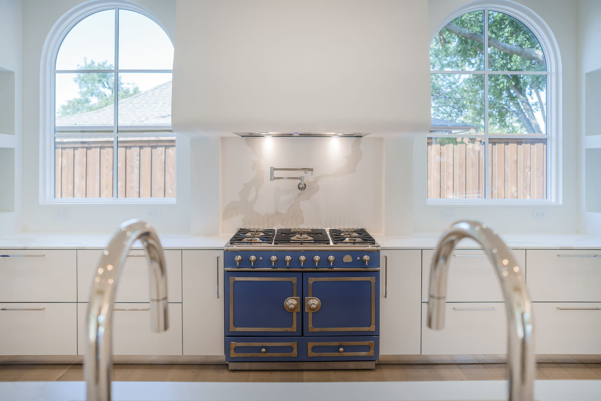 A white kitchen with a blue and gold detailed stove.