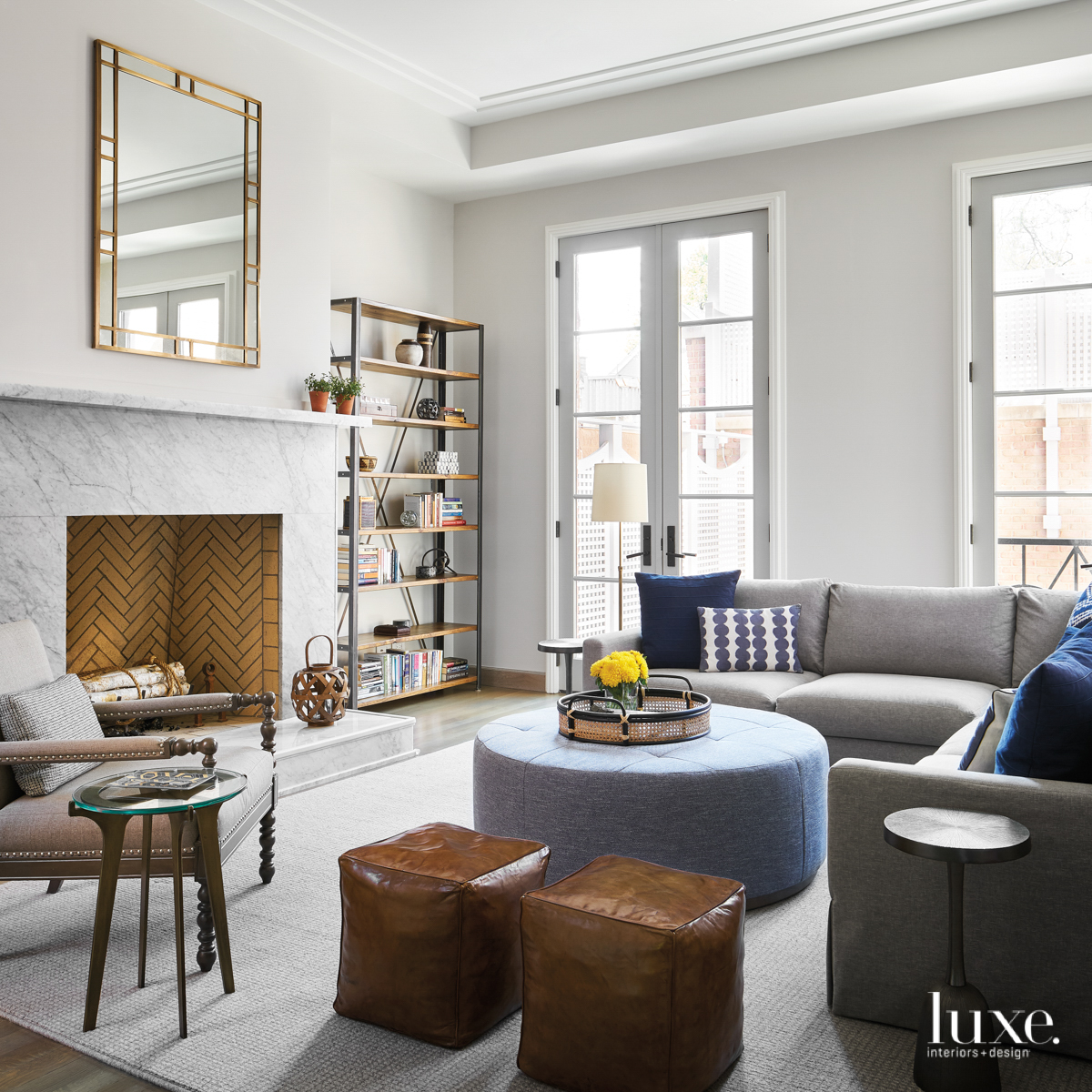 gray living room with marble fireplace and blue ottoman