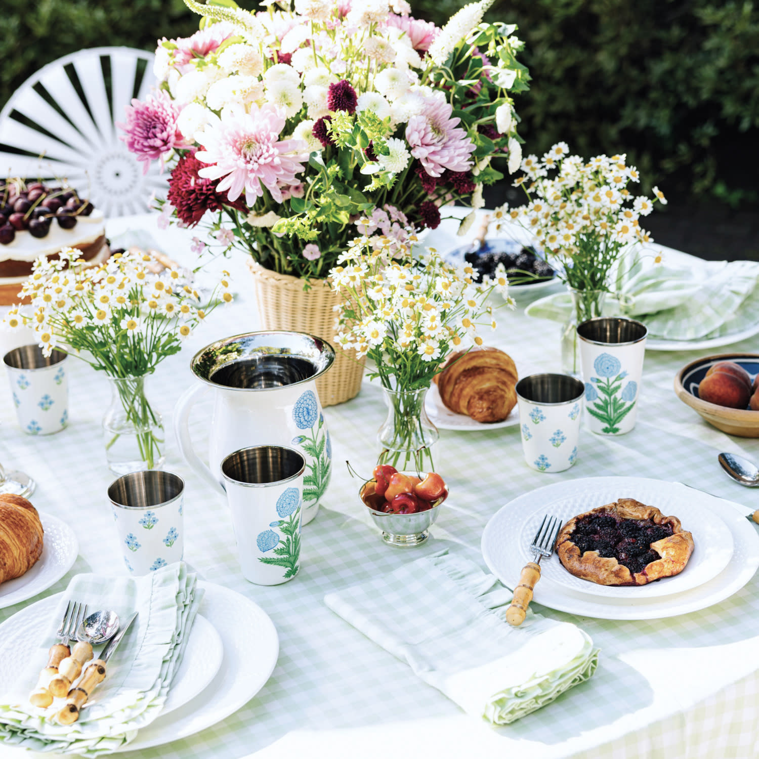 Outdoor tablescape of blue floral cups and sage green checked napkins and tablecloth