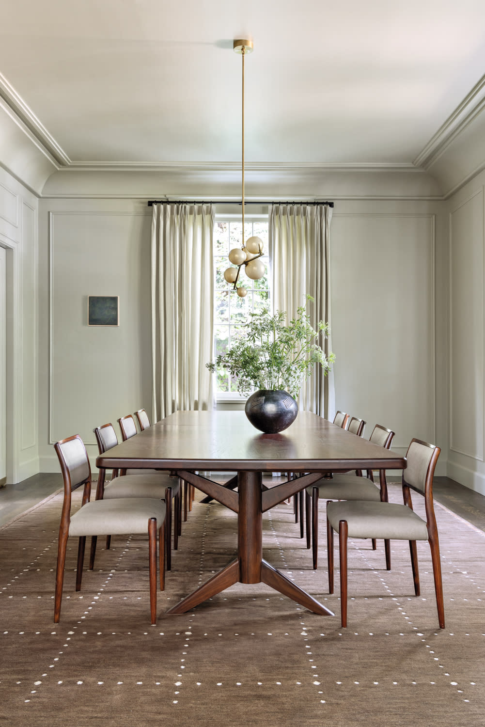 A bright dining room with a round table and four chairs, adorned with a centerpiece and natural light streaming in.