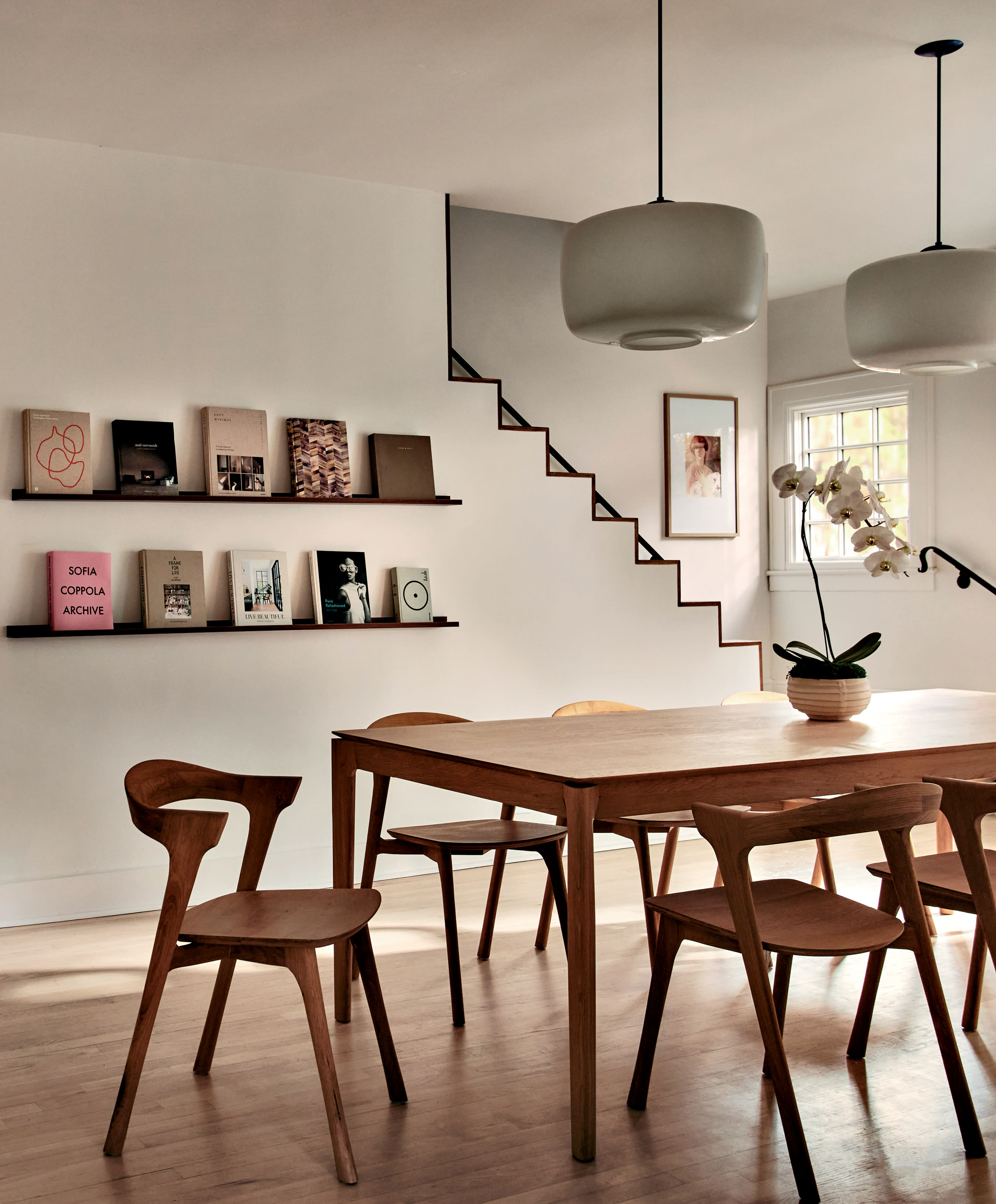 A dining table and matching chairs sit in the center of a room with two bookshelves on the wall.