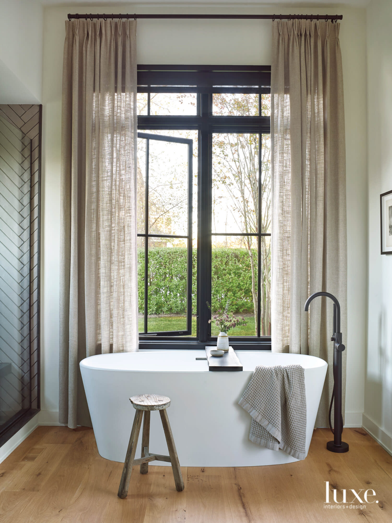 A modern white bathtub defines the calming master bathroom