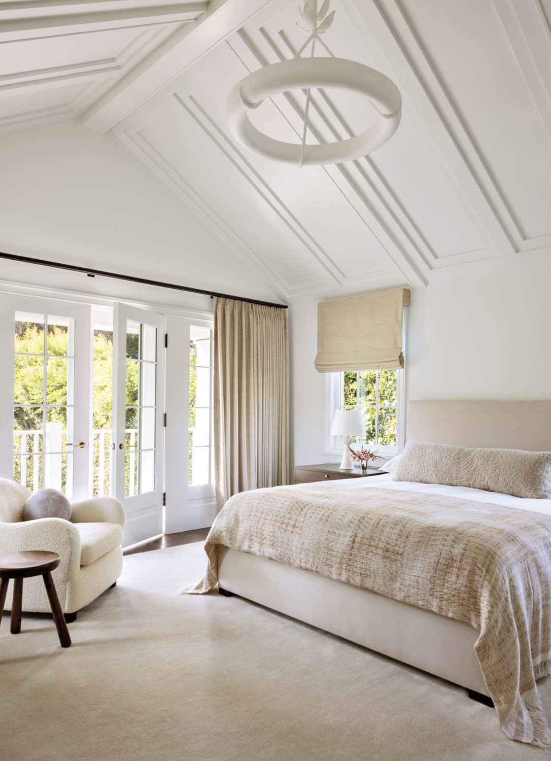 A spacious bedroom featuring a large, neatly made bed with decorative pillows and a soft blanket.
