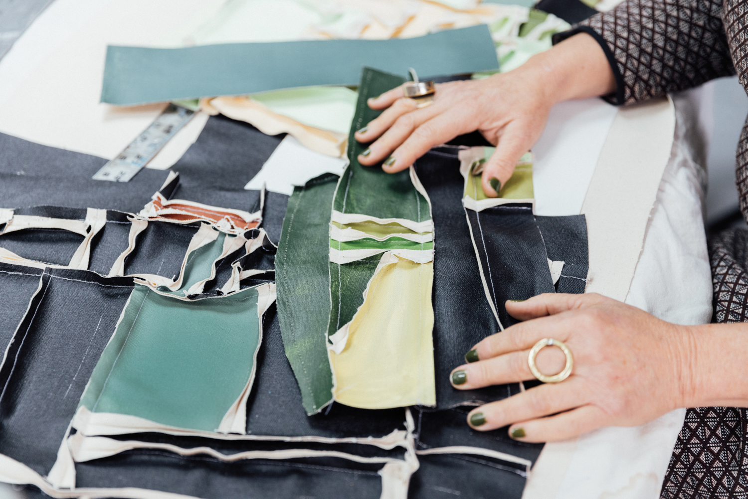 woman's hands rest upon various pieces of fabric sewn together