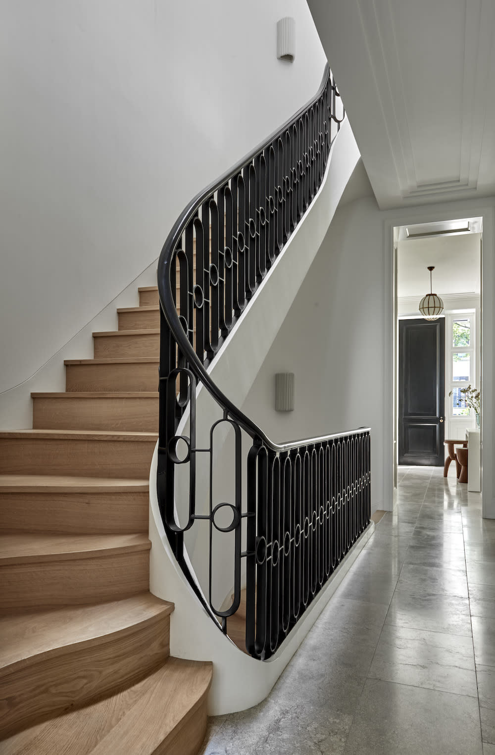 The white walls in this hallways serve as a clean and neutral backdrop allowing the beauty and details of the light wood stairs and black iron railing to standout.