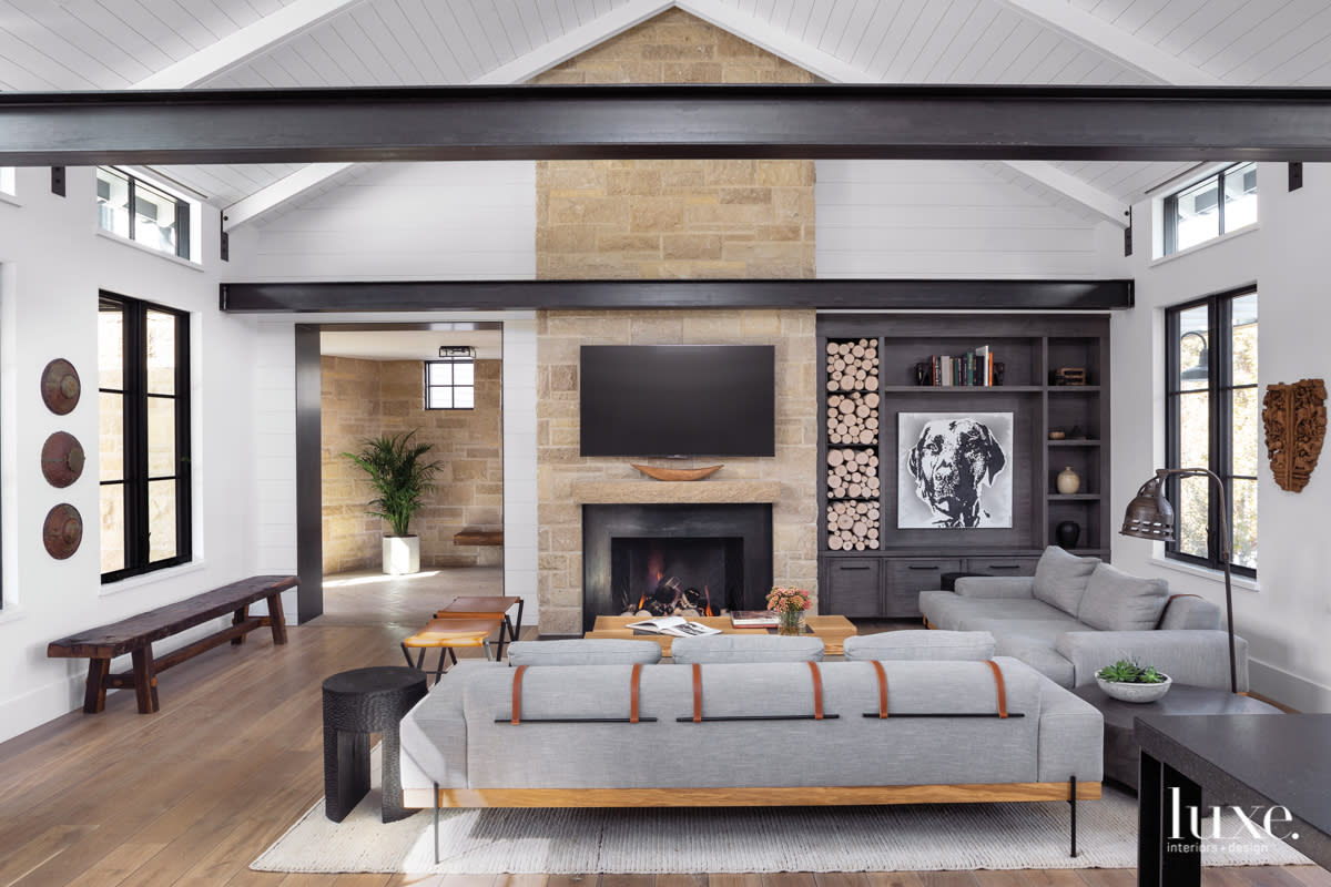 living room with tall fireplace, couch, and dark steel beans across the top