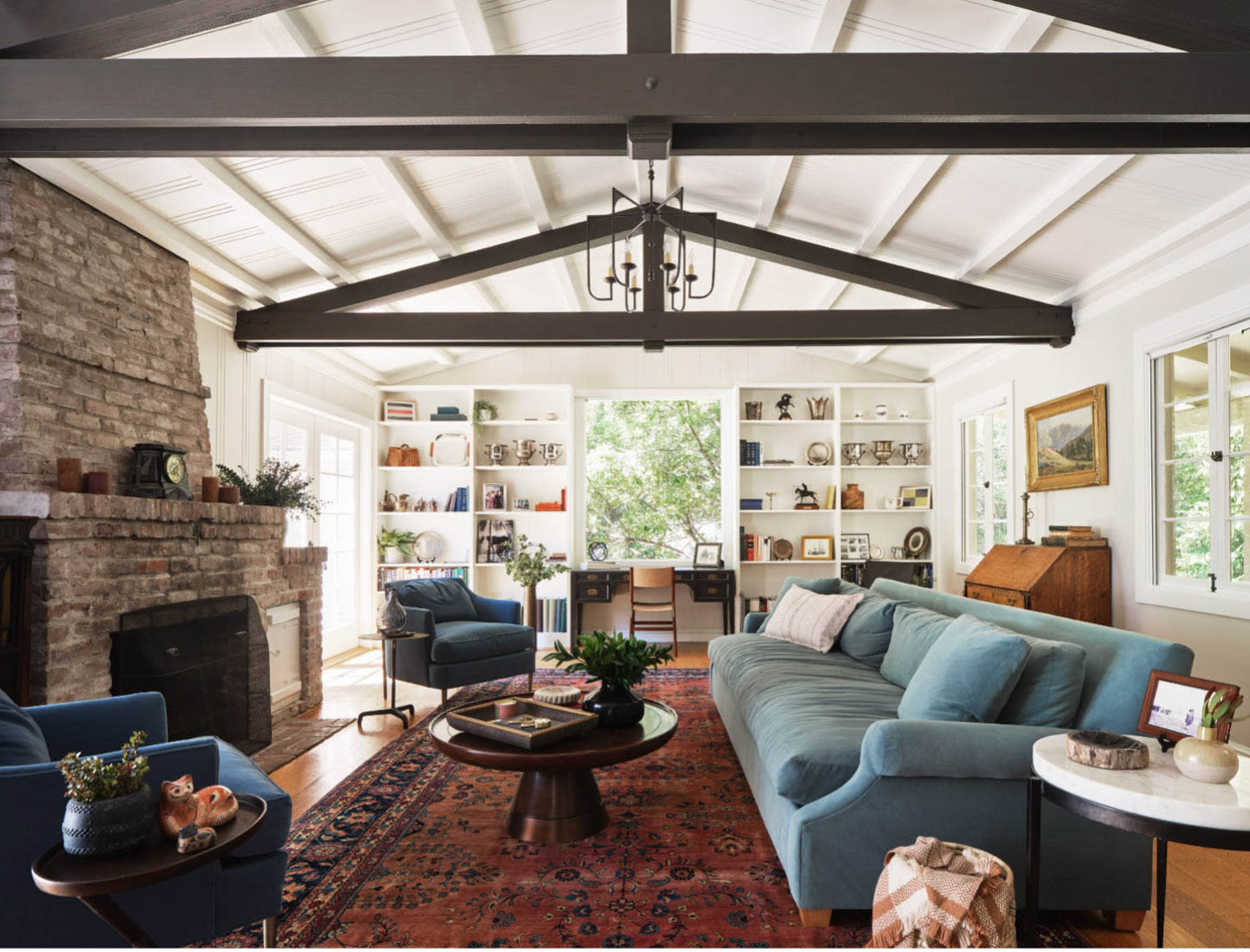 classic living room with built-ins, blue couch, brick fireplace and red rug